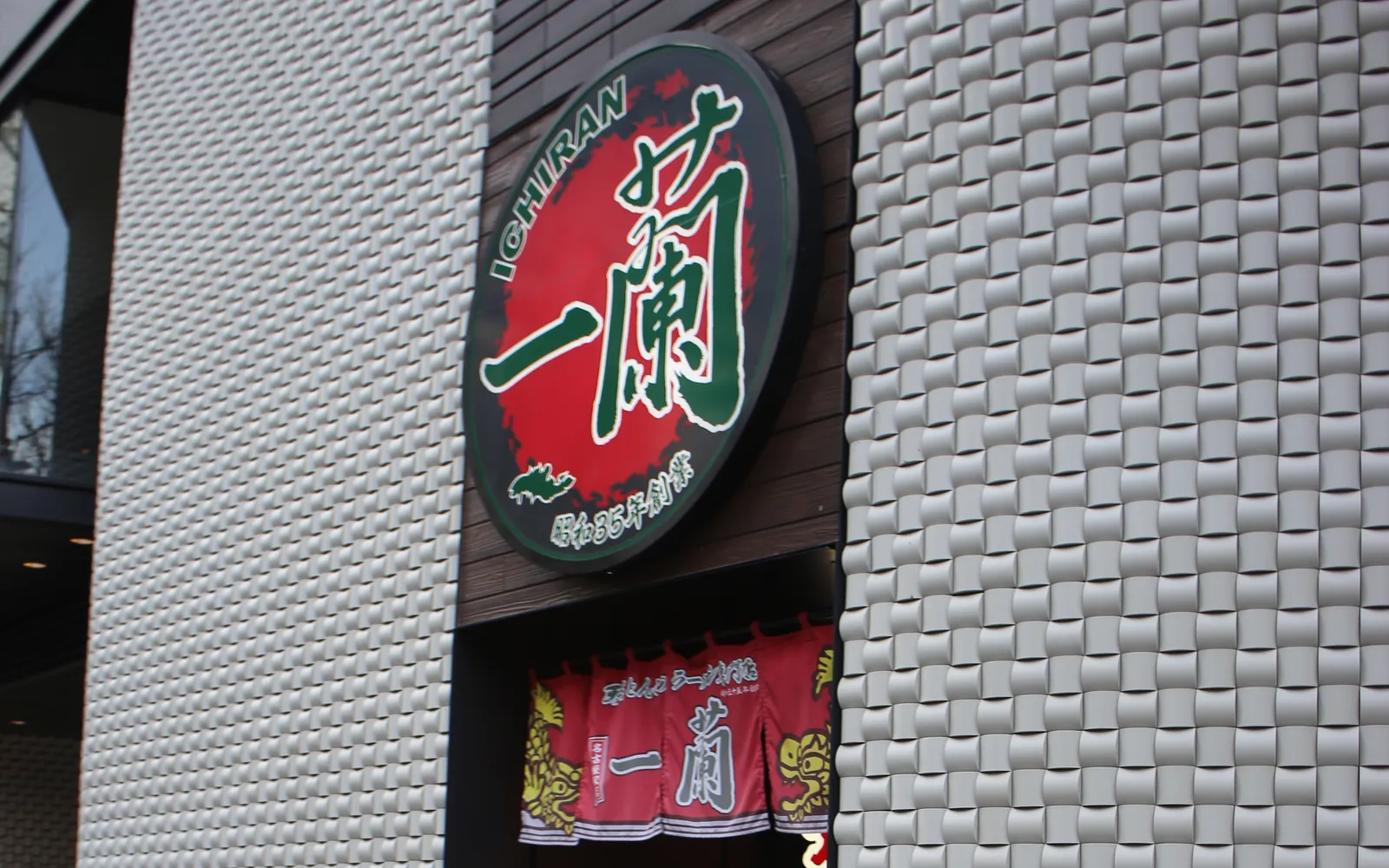 一蘭 名古屋駅店の入口。赤い円の「一蘭」の看板の下に、「一蘭」と書かれた赤いのれんが掛かっている